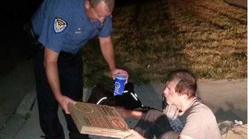 A photo posted to Middletown Division of Police Facebook page showed an officer giving a homeless man a pizza and drink. PHOTO CREDIT: Facebook