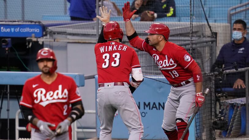 Cincinnati Reds' Jesse Winker (33) celebrates with Joey Votto (19) after Winker hit a home run during the first inning of a baseball game against the Los Angeles Dodgers Tuesday, April 27, 2021, in Los Angeles. (AP Photo/Ashley Landis)