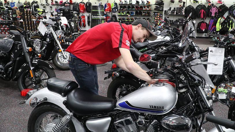 Reese Shafer polishes a motorcycle in the showroom at Ride 1 Powersports on Leffel Lane Wednesday. BILL LACKEY/STAFF