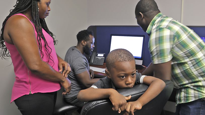 Kepler Jean Baptiste looks around the room as Malachi Thebaud, a bilingual assistant, right, helps his father, Jean Paul Jean Baptiste, and mother, Eveline Port Louis, register him for school in the Springfield City School District Tuesday, August 1, 2023. BILL LACKEY/STAFF