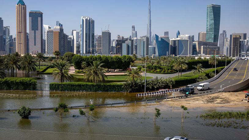 FILE - An abandoned vehicle stands in floodwater caused by heavy rain with the Burj Khalifa, the world's tallest building, seen on the background, in Dubai, United Arab Emirates, on April 18, 2024. Dubai Airports announced on Thursday, May 2, the cancelation and diversion of flights due to unsettled weather conditions in the United Arab Emirates. (AP Photo/Christopher Pike, File)