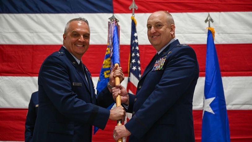 U.S. Air Force Brig. Gen. David Johnson passes the guidon to Col. Donald Braskett (right) during a change of command ceremony on Springfield-Beckley Air National Guard Base, Ohio, April 7, 2024. As the commander, he executes the remotely piloted aircraft MQ-9 Reaper mission. (U.S. Air National Guard photo by Airman 1st Class Josh Kaeser)