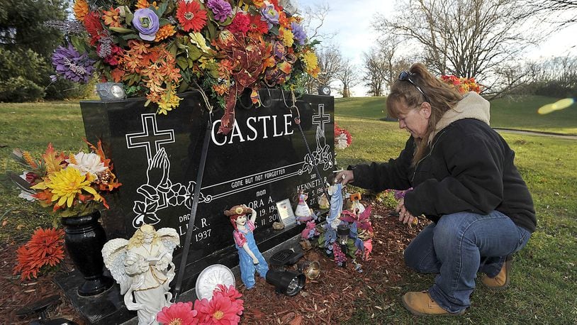 Barbara Castle straightens some of the items surrounding her mother’s grave at Ferncliff Cemetery on Wednesday evening. Castle is upset because someone has been stealing the solar lights that she’s placed around the grave marker because her mother was afraid of the dark. Bill Lackey/Staff