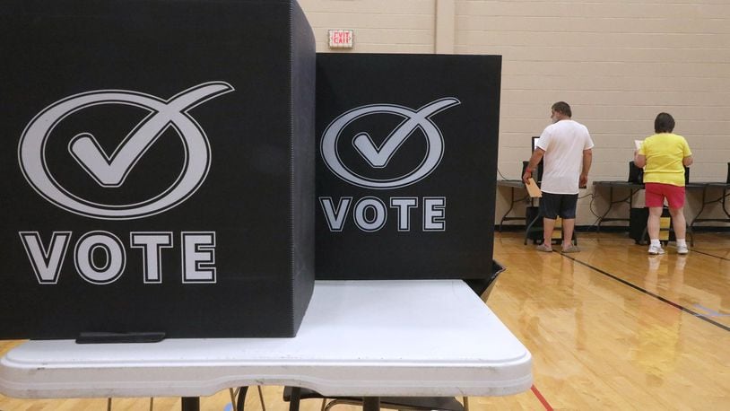Voters place their ballots in the voting machines at the New Carlisle election poll in Tecumseh High School. BILL LACKEY/STAFF