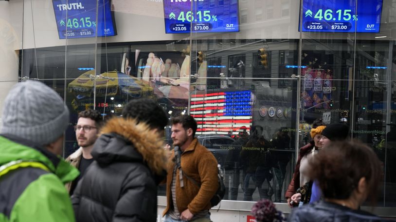 FILE - Pedestrians walk past the Nasdaq building as the stock price of Trump Media & Technology Group Corp. is displayed on screens, March 26, 2024, in New York. A Delaware judge on Tuesday, April 30, granted a request by attorneys for Donald Trump and Trump Media & Technology Group, parent company of his Truth Social platform, to slow down a lawsuit filed by two cofounders of the company. (AP Photo/Frank Franklin II, File)