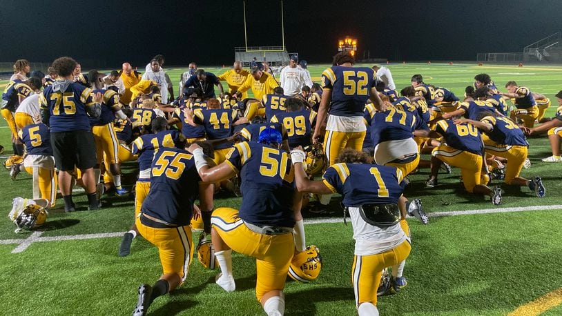 Springfield players kneel around coach Maurice Douglass after a victory against Saint Ignatius on Friday, Aug. 20, 2021, at Springfield High School. David Jablonski/Staff