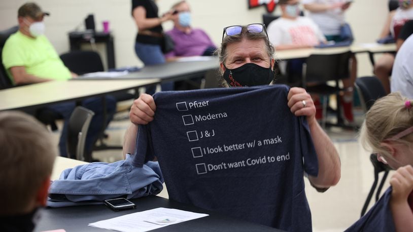 A man holds up a t-shirt he received after getting his COVID vaccination at Tecumseh High School. BILL LACKEY/STAFF