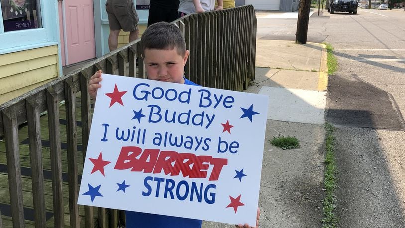 Reese Carter holds a sign supporting his friend and classmate, Barrett Fitzsimmons, who lost his battle with cancer Tuesday. Carter was one of several community members who lined the streets of the village of North Hampton as Fitzsimmons funeral procession passed on Saturday. BRETT TURNER / CONTRIBUTED