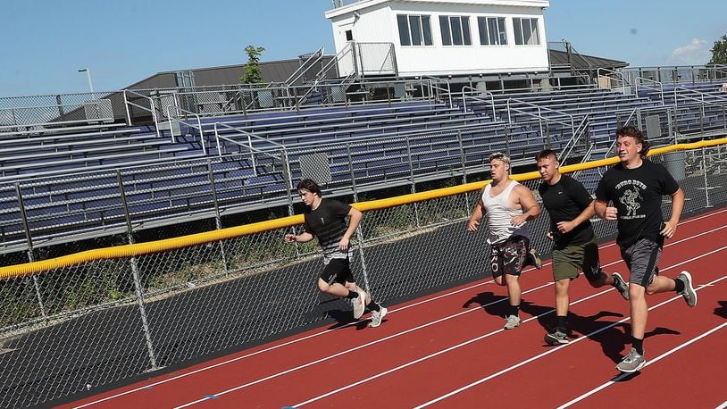 Senior football players at Mechanicsburg High School run past the empty bleachers at the school’s stadium Thursday. With the Coronavirus pandemic, its not clear if fans will be in the stands for games this season. BILL LACKEY/STAFF
