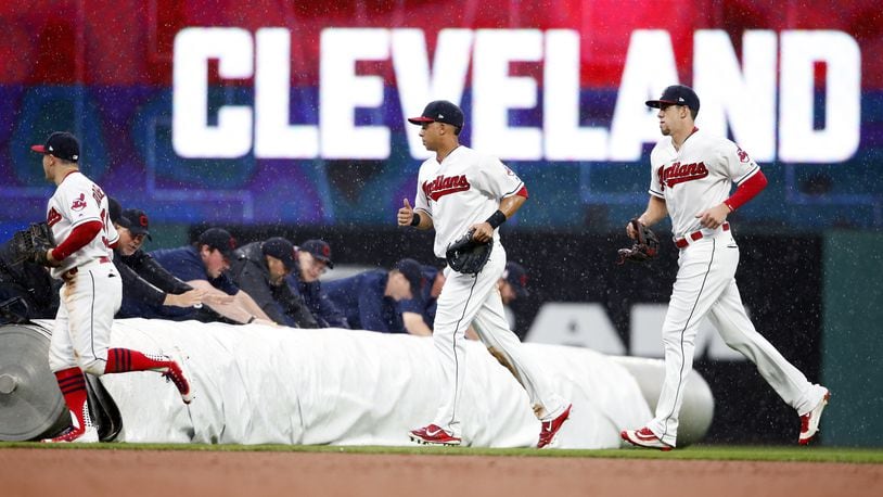 CLEVELAND, OH - MAY 24: Daniel Robertson #99 Michael Brantley #23 and Bradley Zimmer #4 of the Cleveland Indians run to the dugout as the grounds crew rolls out the tarp due to heavy rain against the Cincinnati Reds during the sixth inning at Progressive Field on May 24, 2017 in Cleveland, Ohio. (Photo by Ron Schwane/Getty Images)