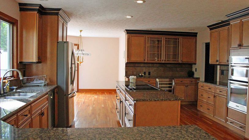 The open kitchen features granite countertops, hardwood floors, a center island and plenty of wood cabinetry.