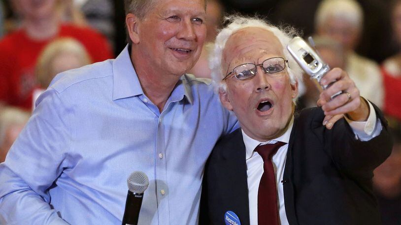 Republican presidential candidate, Ohio Gov. John Kasich poses for a selfie with a Bernie Sanders impersonator at the end of a town hall meeting, Wednesday, March 9, 2016, in Palatine, Ill. (AP Photo/Charles Rex Arbogast)