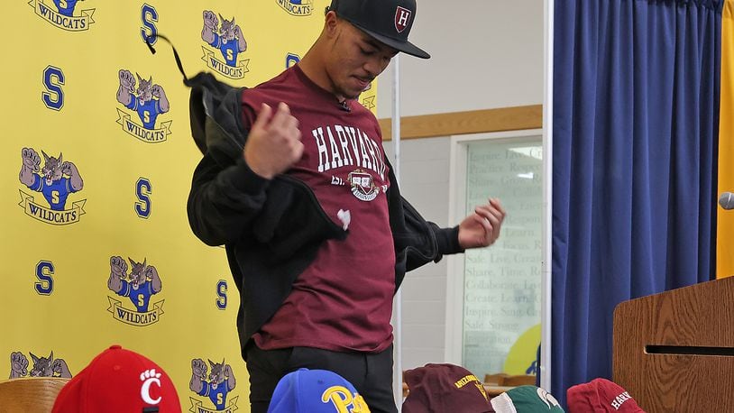 Springfield High School football standout Delian Bradley takes off his jacket to reveal his college selection Wednesday during National Signing Day. Delian chose Harvard from the 31 college scholarship offers. BILL LACKEY/STAFF