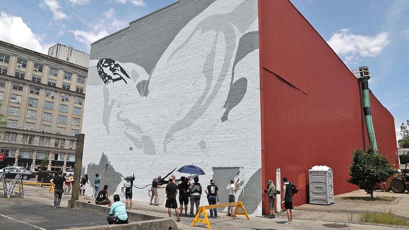 Work has started on a mural on the back wall of The State theater in downtown Springfield Wednesday, June 1, 2022. A television production crew was filming people working on the mural Wednesday. BILL LACKEY/STAFF