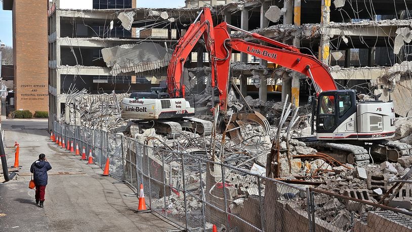 A woman walks down an alley as a crew from Tony Smith Wrecking tears down the Bushnell Parking Garage. BILL LACKEY/STAFF