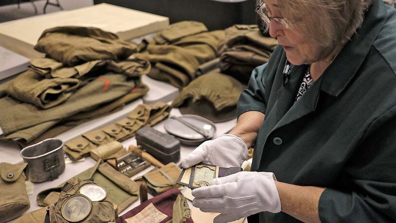 Virginia Weygandt, Director of Collections for the Clark County Historical Society, opens a small soldiers wallet with a tiny picture still inside as she goes over items for the new WWI exhibit. Bill Lackey/Staff