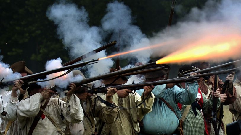 Fire explodes from a row of militia muskets as the militiamen in the 225th anniversary re-enactment of the Battle of Peckuwe take aim at the Native American warriors Sunday, July 17, 2005, at George Rogers Clark Park in Springfield, Ohio. The re-enactment commemorates the largest Revolutionary War battle fought west of the Allegheny Mountains which took place on the site of the current county park. Bill Lackey/Staff