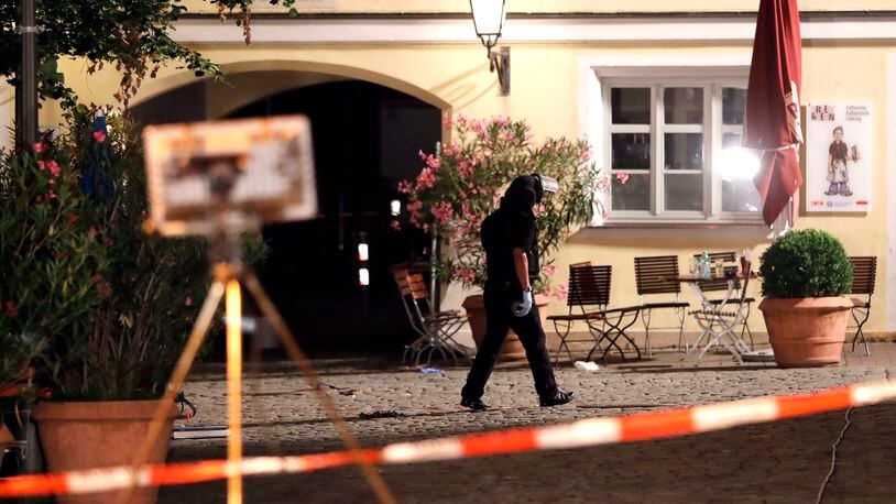 A special police officer examines the scene after an explosion occurred in Ansbach, Germany, Monday, July 25, 2016. Bavaria's top security official says a man who blew himself up after being turned away from an open-air music festival in the southern German city was a 27-year-old Syrian who had been denied asylum. (AP Photo/Matthias Schrader)