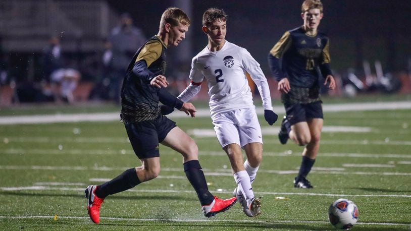 Cutline: Greenon High School senior Jeremiah Mauch (center) passes the ball to a teammate during a Division III district final match against Botkins on Thurdsay night at Bellefontaine High School. The Trojans won 2-1. CONTRIBUTED PHOTO BY MICHAEL COOPER
