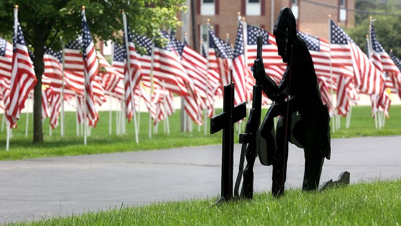 A wooden cutout of a soldier kneeling at a comrade's grave stands out against the American flags in the Honor Field memorial display at Jackson Lytle & Lewis Life Celebration Center in Springfield in this file photo. BILL LACKEY/STAFF
