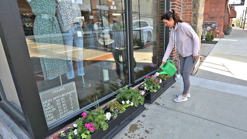 Kristine Baggs, owner of the new Firefly Boutique in downtown Springfield, waters the flowers in front of her business along North Fountaine Avenue Wednesday, April 27, 2022. The boutique, featuring women's clothing and jewelry, will have a soft opening Friday and a grand opening on May 6 for First Friday in downtown. BILL LACKEY/STAFF