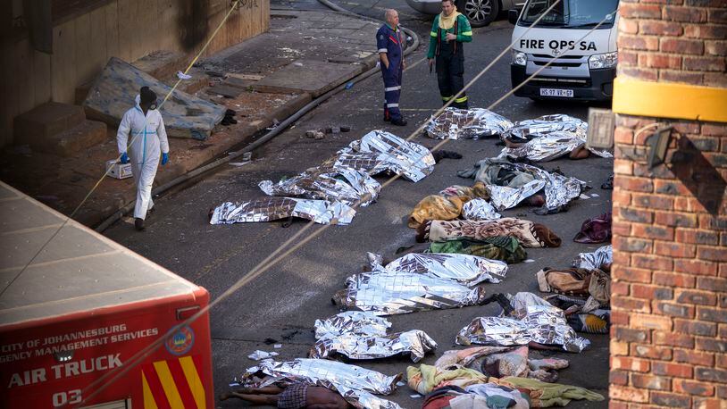 FILE - Medics stand by the covered bodies of victims of a deadly blaze in Johannesburg, Thursday, Aug. 31, 2023. A report into a building fire that killed 76 people in South Africa last year has concluded that city authorities should be held responsible because they were aware of serious safety issues at the rundown apartment block at least four years before the blaze. The nighttime fire at the five-story building in downtown Johannesburg on Aug. 31 was one of South Africa's worst disasters. At least 12 children were among the dead and another 86 people were injured. (AP Photo/Jerome Delay/File)