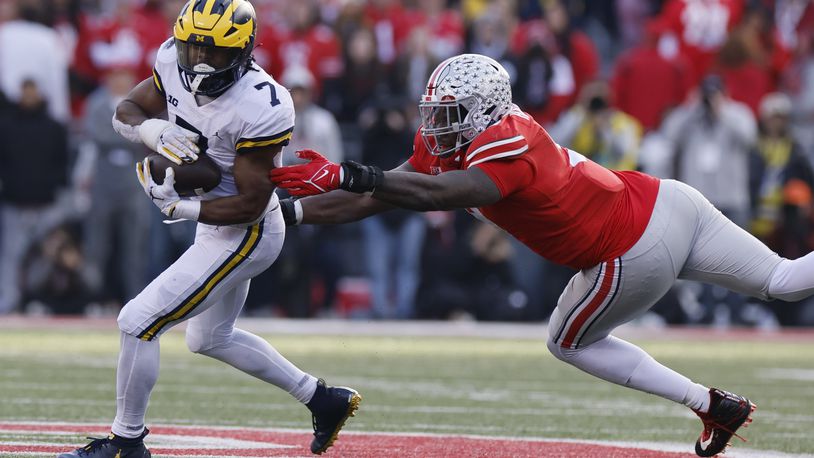 Michigan running back Donovan Edwards, left, turns up field past Ohio State defensive lineman Zach Harrison during the second half of an NCAA college football game on Saturday, Nov. 26, 2022, in Columbus, Ohio. (AP Photo/Jay LaPrete)