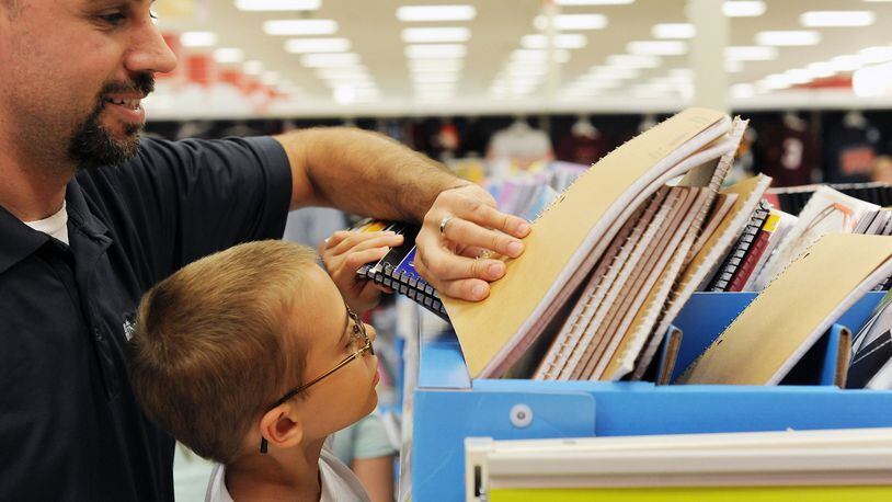 Jason Moore, left, helps his 8-year-old son Jackson Moore pick out a spiral notebook during tax-free shopping at Target on Friday, Aug. 2, 2013 in Lynchburg, Va. (AP Photo/News & Daily Advance, Sam O’Keefe)