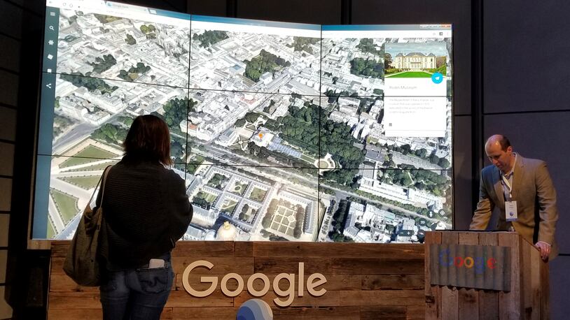 Sean Askay, right, engineering manager with Google Earth, demonstrates features on Google Earth, displayed in background, Tuesday, April 18, 2017, in New York. Google Earth is getting a revival, with the mapping service becoming more of a tool for adventure and exploration. (AP Photo/Anick Jesdanun)