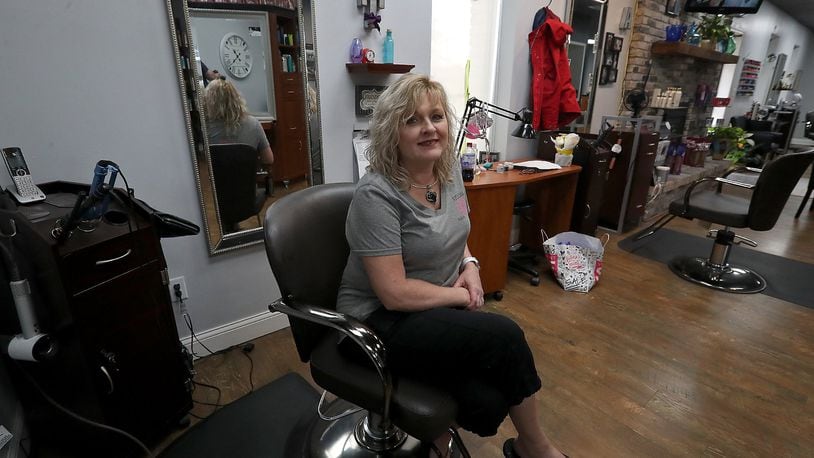 TaBetha Biggs, owner of Studio B Salon and Spa, sits at her station in her empty salon Tuesday. As the governor starts the state’s economy back up, local stylists and barbers are left wondering when they can reopen. BILL LACKEY/STAFF