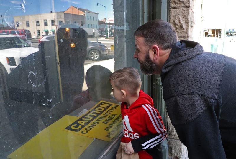 Trent Spriggs and his son, Tyrion, peak through one of the windows of the Douglas Hotel as they check out the renovations going on inside Friday. BILL LACKEY/STAFF