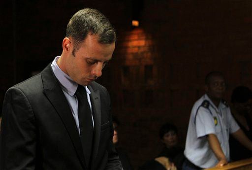 Olympic athlete Oscar Pistorius stands inside the court as a police officer looks on.