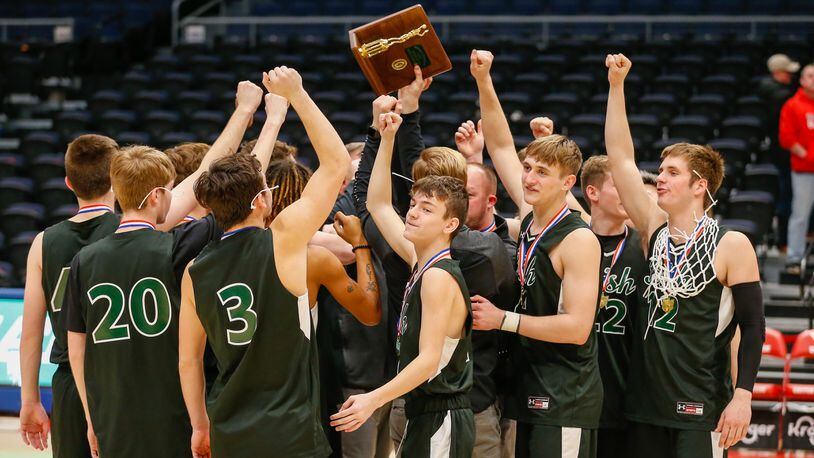 The Catholic Central boys basketball team celebrates with trophy after beating Jackson Center to win its third district title in five years. CONTRIBUTED PHOTO BY MICHAEL COOPER
