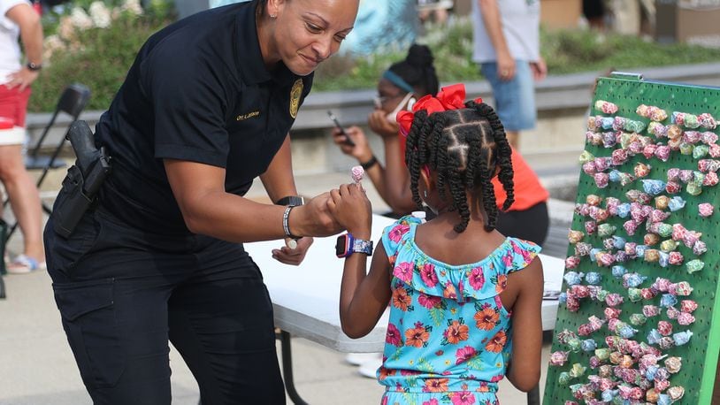 Springfield Police Officer Amanda Jackson gives a young girl a piece of candy for winning a game during the National Night Out in Springfield Tuesday, August 2, 2022. City leaders want to increase police hiring in 2023 under the proposed budget. BILL LACKEY/STAFF