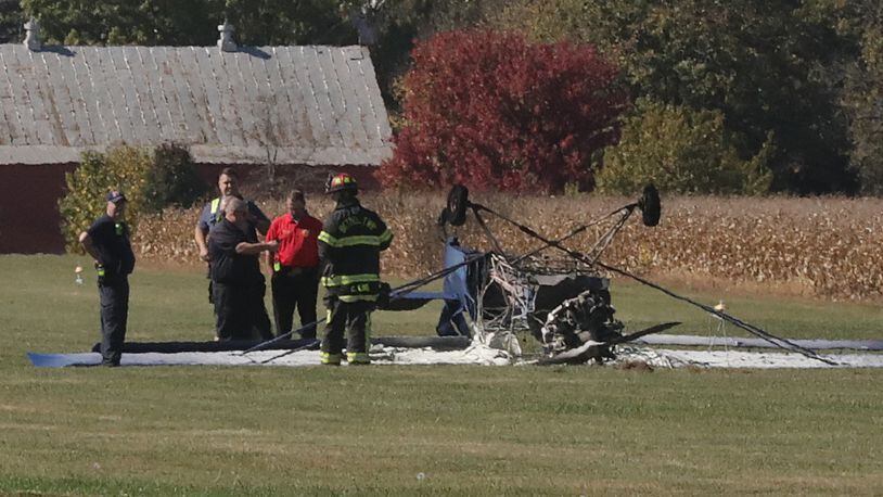 Emergency personnel look over the remains of a single engine airplane that crashed while landing and burst into flames at the New Carlisle Airport Tuesday, Oct. 13, 2020. Bystanders rescued the pilot and passenger from the plane. BILL LACKEY/STAFF