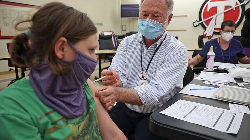 Dr. John Dobson gives Bella Handwerker, 12, her COVID vaccination during a COVID clinic at Tecumseh High School. BILL LACKEY/STAFF