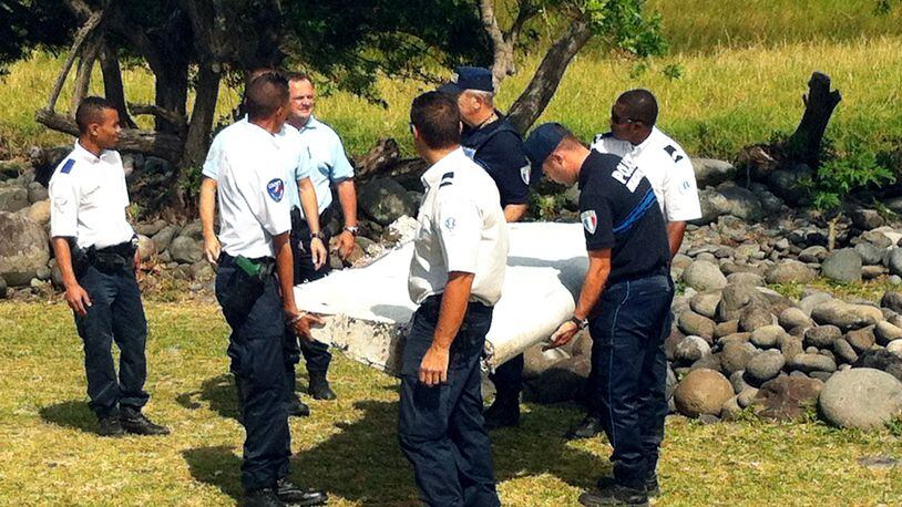 Police and gendarmes carry a piece of debris from an unidentified aircraft found in the coastal area of Saint-Andre de la Reunion, in the east of the French Indian Ocean island of La Reunion, on July 29, 2015. The two-metre-long debris, which appears to be a piece of a wing, was found by employees of an association cleaning the area and handed over to the air transport brigade of the French gendarmerie (BGTA), who have opened an investigation. An air safety expert did not exclude it could be a part of the Malaysia Airlines flight MH370, which went missing in the Indian Ocean on March 8, 2014. (Photo: YANNICK PITOU/AFP/Getty Images)