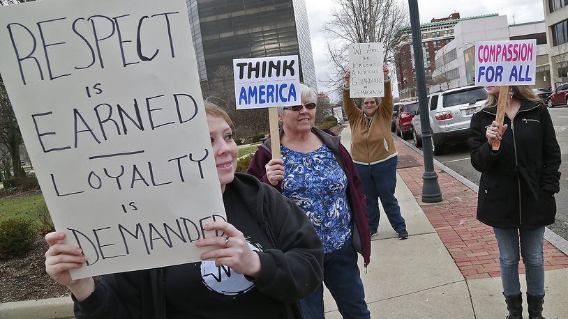 A small group of Donald Trump protestors, including Chelsea LeMaster, left, stand on the corner of Limestone and High Streets with protest signs Friday. Bill Lackey/Staff
