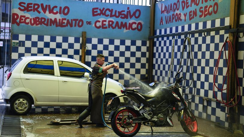 A worker washes a motorcycle at an ecological carwash in Bogota, Colombia, Friday, April 12, 2024. Water rationing in the capital began on Thursday due to the low level of water in reservoirs that give drinking water to the capital, a consequence of the El Niño weather phenomenon. (AP Photo/Fernando Vergara)