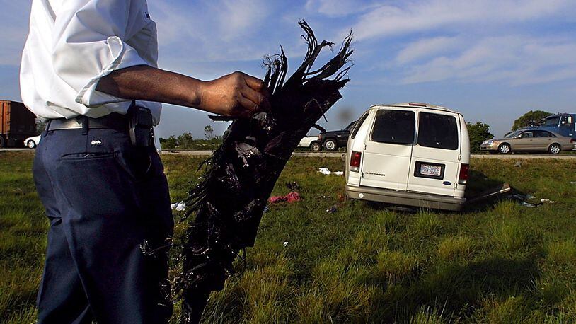 Road Ranger driver Eugene Smith picks up a large part of a tire from the median of I-95 at the 92 mile marker, three miles south of Hobe Sound, after a Ford Clubwagon loaded with 15 migrant workers blew its right rear tire and rolled over Tuesday, April 2, 2002. Although numerous occupants were ejected from the vehicle, none sustained life-threatening injuries. Staff photo by Chris Matula