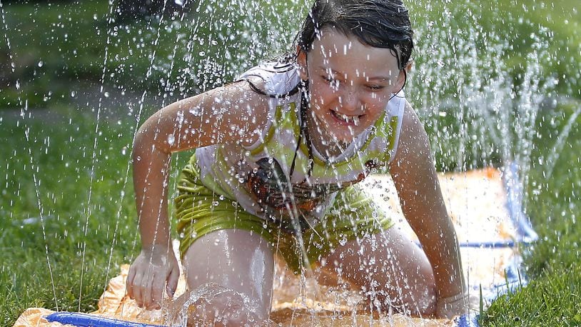 Lacie Jessee, 6, slides across her front yard along McCreight Avenue on a water slide Monday, June 12, 2017, as she tries to stay cool. BILL LACKEY/STAFF