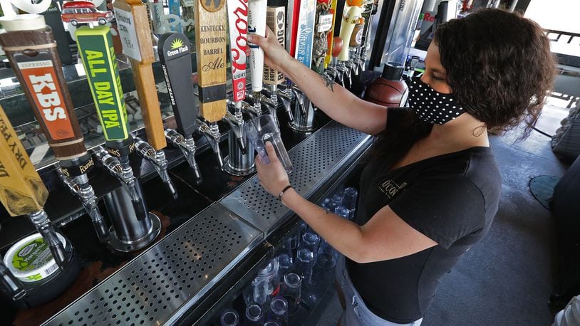 Nikki Callicoat pours a draft beer behind the bar at O'Conner's Irish Pub Friday. BILL LACKEY/STAFF