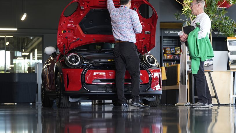 FILE - This photo provided by the Associated Press shows a salesperson shows an unsold 2024 Cooper SE electric hardtop to a prospective buyer as the vehicle sits on display on the showroom floor of a Mini dealership, Wednesday, May 1, 2024, in Highlands Ranch, Colo. (AP Photo/David Zalubowski, File)