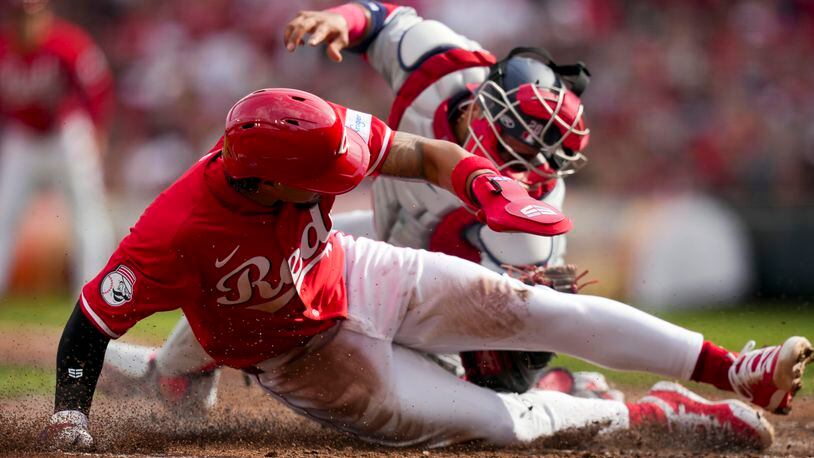 Cincinnati Reds' Santiago Espinal, front, is tagged out at home plate by Washington Nationals' Keibert Ruiz, back, during the second inning of a baseball game in Cincinnati, Saturday, March 30, 2024. (AP Photo/Aaron Doster)