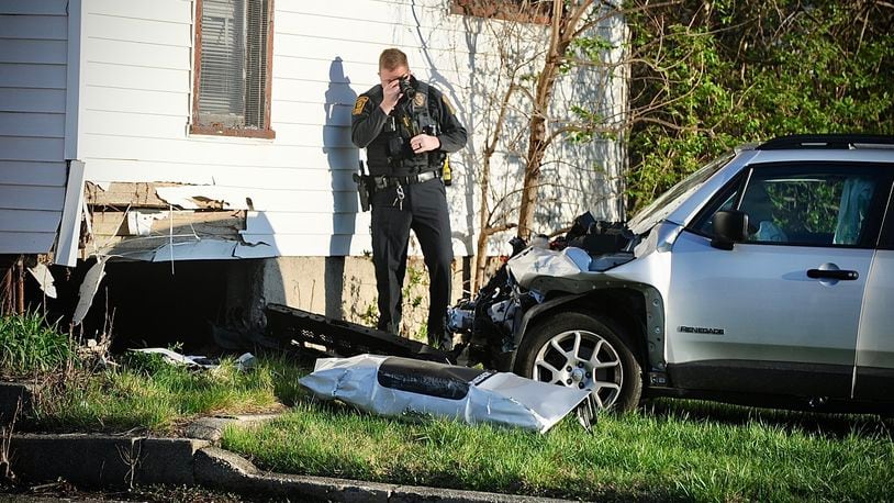 A member of the Springfield Police Division take photos of a Jeep that struck a house on West Pleasant Street early Wednesday morning, April 3, 2024. Driver of the vehicle transported by squad to local hospital. The accident remains under investigation. MARSHALL GORBY \STAFF