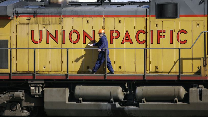 FILE - A maintenance worker walks past the company logo on the side of a locomotive in the Union Pacific Railroad fueling yard in north Denver, Oct. 18, 2006. Union Pacific dramatically reduced its use of temporary limits on some businesses' shipments over the past year after its customers complained, but regulators said Wednesday, April 17, 2024, that the railroad must go further to be in line with the other major freight railroads that rarely use such embargoes. (AP Photo/David Zalubowski, File)