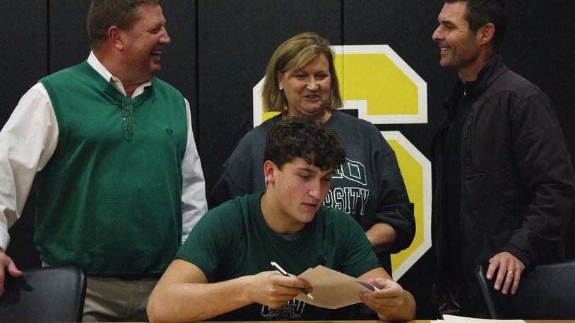 Shawnee linebacker Jack McCrory signs with Ohio University on Wednesday in the company of Braves coach Rick Meeks (left) and his parents Tony and Phyllis McCrory. JEFF GILBERT / CONTRIBUTED