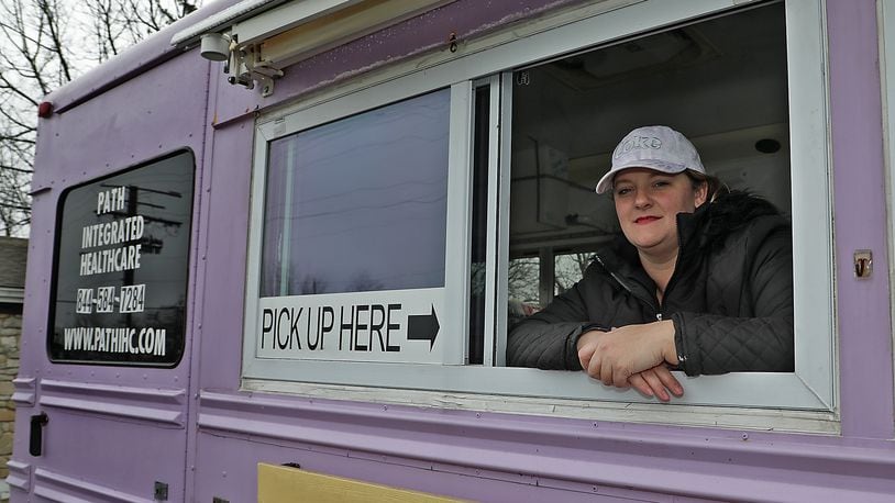 Mandy Gabbert, from Path Integrated Healthcare, in the purple bus they serve free dinners out of for homeless and hungry people. BILL LACKEY/STAFF