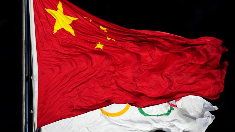 FILE - The Chinese and the Olympic flag wave during the opening ceremony of the 2022 Winter Olympics, Feb. 4, 2022, in Beijing. In the two years before the World Anti-Doping Agency cleared 23 Chinese swimmers of doping allegations, that country’s government contributed nearly $2 million in additional funding to WADA programs, including one designed to strengthen the agency’s investigations and intelligence unit. (AP Photo/Petr David Josek, file)