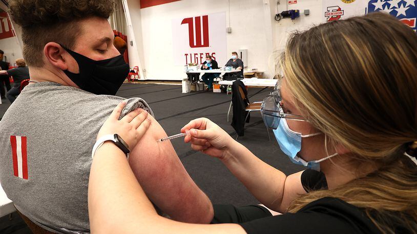 Logan Lange, a junior at Wittenberg University, gets his COVID vaccine from Wittenberg student nurse Camille Odle on April 9 in the Pam Evans Smith Arena on the Wittenberg campus. On Friday, Clark County's health commissioner said COVID-19 cases are falling in the county because more people are getting vaccinated. BILL LACKEY/STAFF